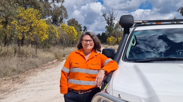 Woman in hi-vis leaning against 4WD vehicle