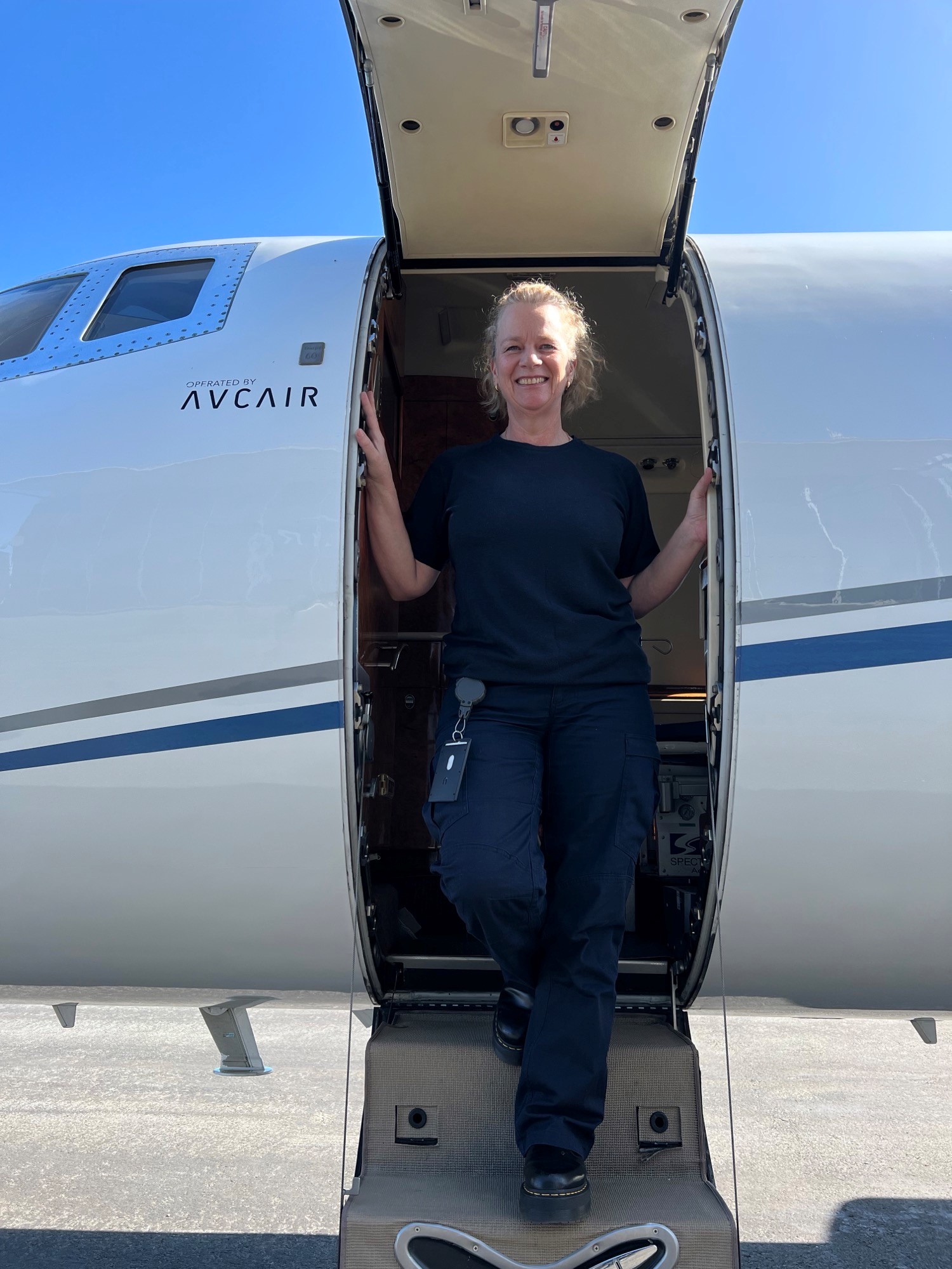 Woman at top of stairs of a Lear Jet looking out through the open door