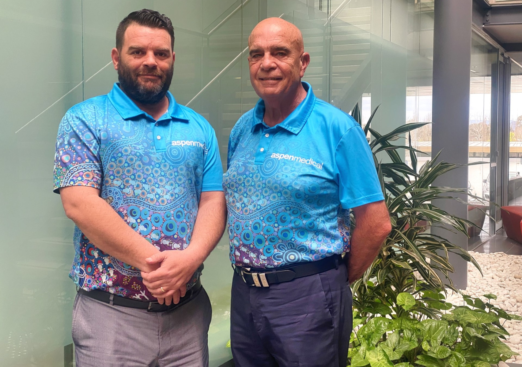 Two men standing side by side in an office building 