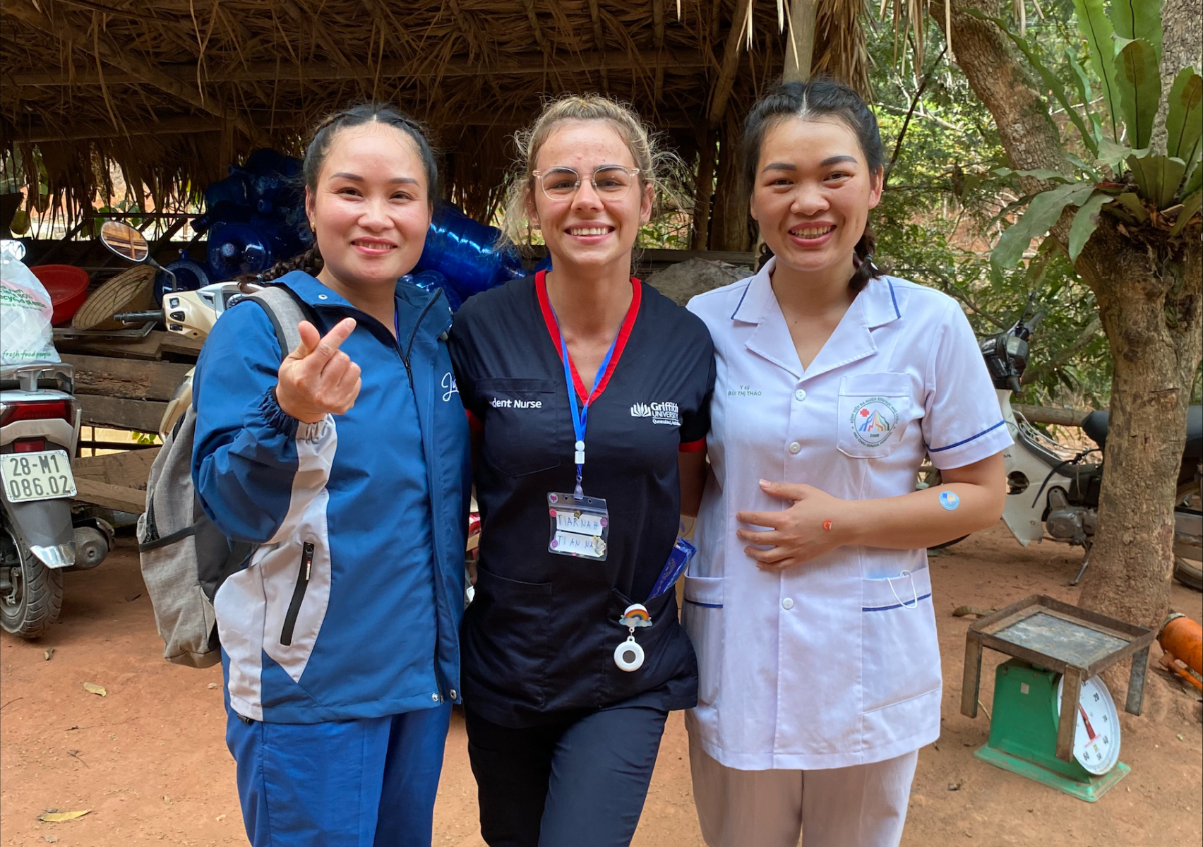 Three female clinicians stand arm in arm in a rural metro setting 