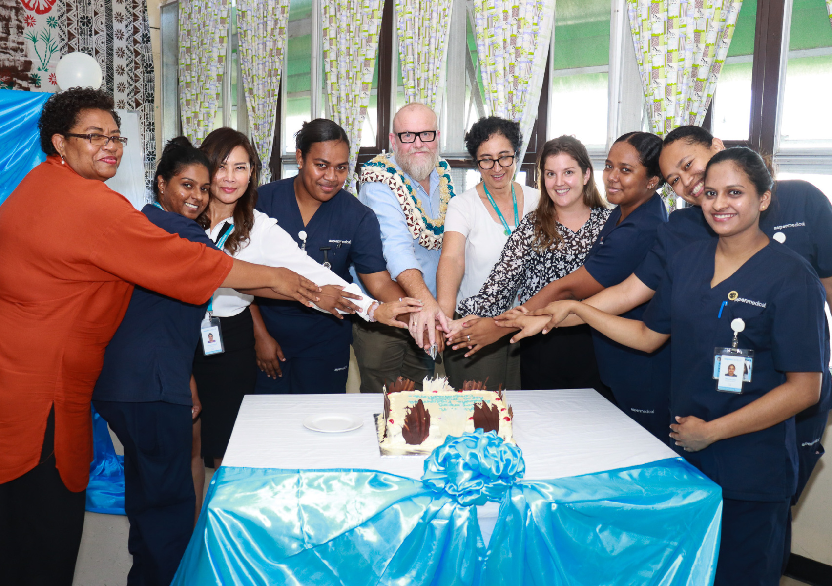 Men and women cutting a celebration cake 
