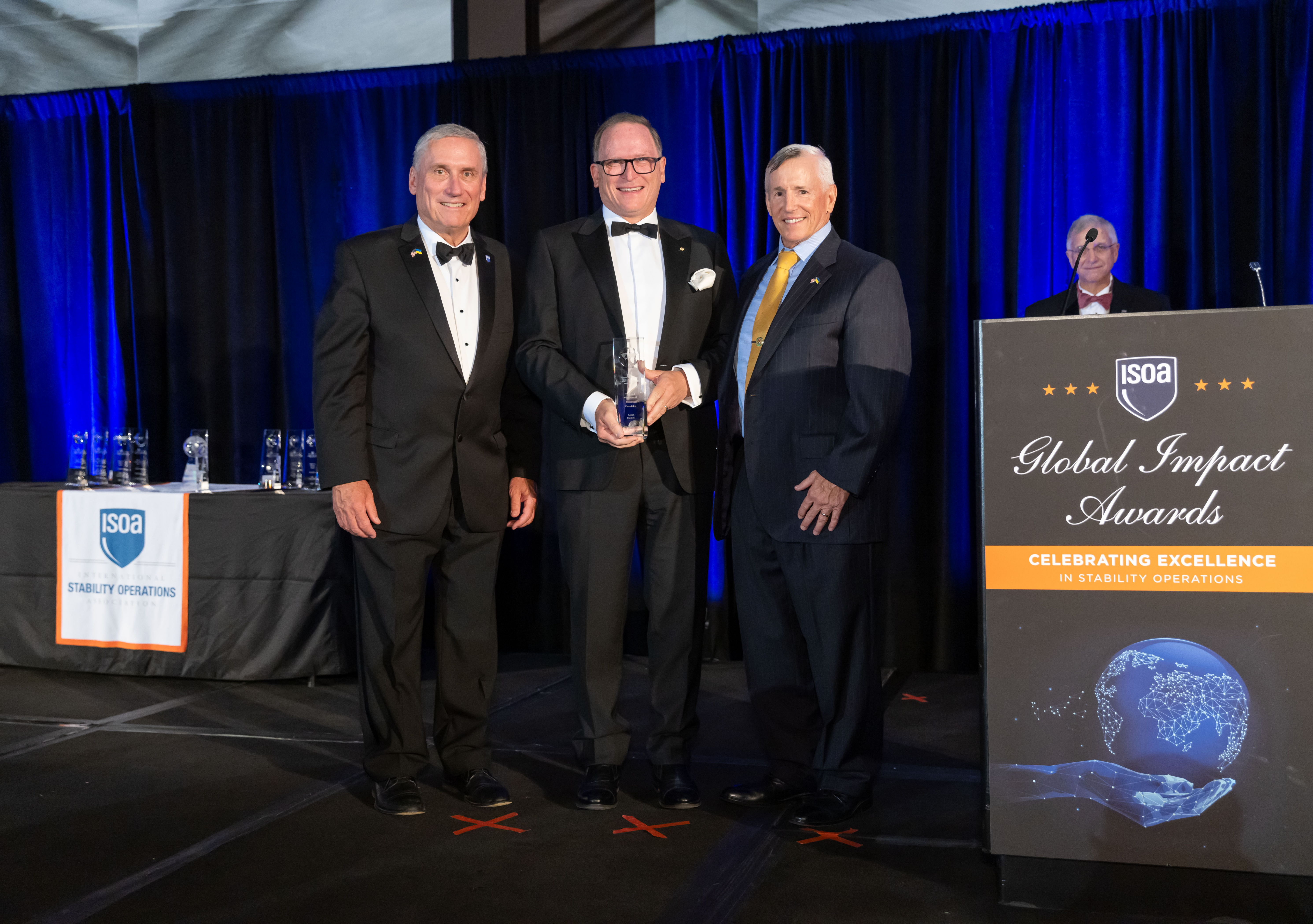 Three men on stage at a corporate awards ceremony