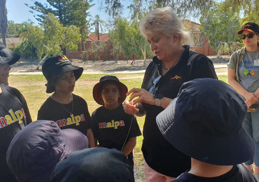 Adult doing a show and tell with school children outdoors