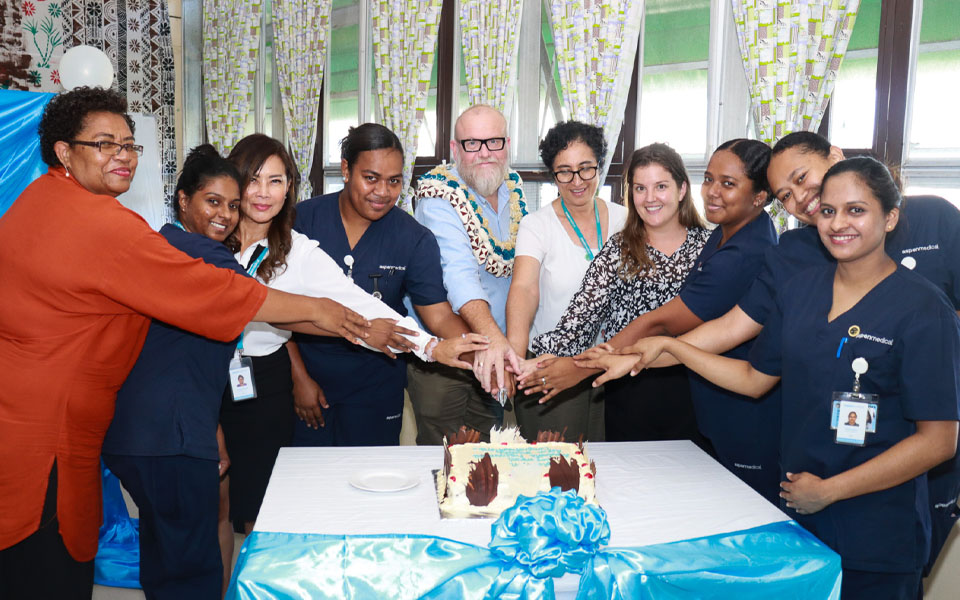 Members of the Aspen Medical clinical and operations team in Fiji with nurses from the Aspen Medical Graduate Nurses Program, putting their hands together to symbolise a team effort.