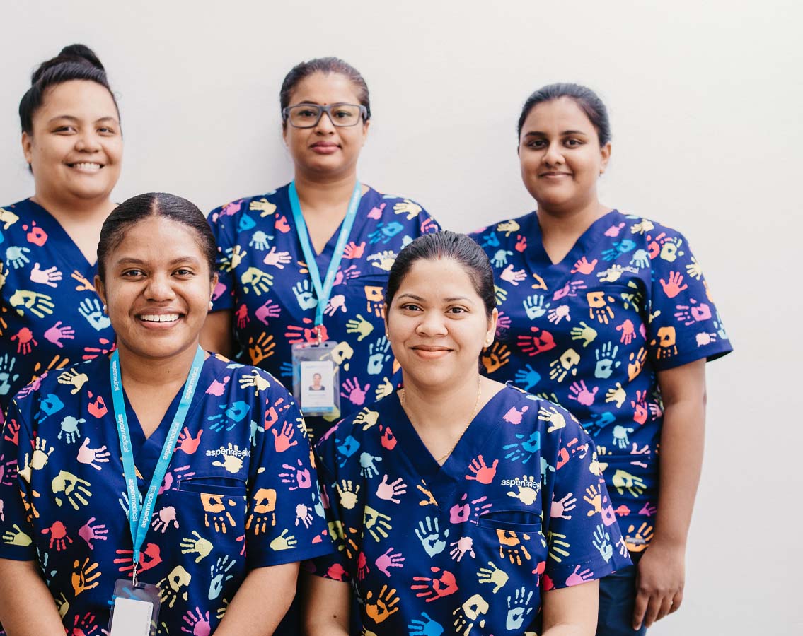 Photo of 5 Aspen Medical Fiji clinicians wearing bring scrubs.