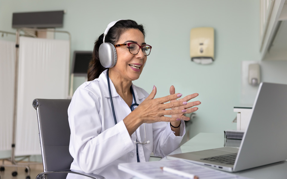 Photo of a female clinician speaking with a patient virtually, using her hands to explain something.