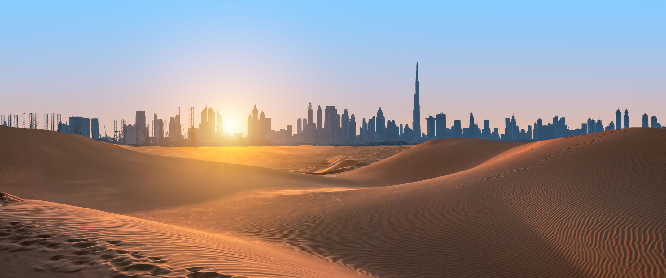 Image of desert surrounding Dubai with city silhouette in the background.