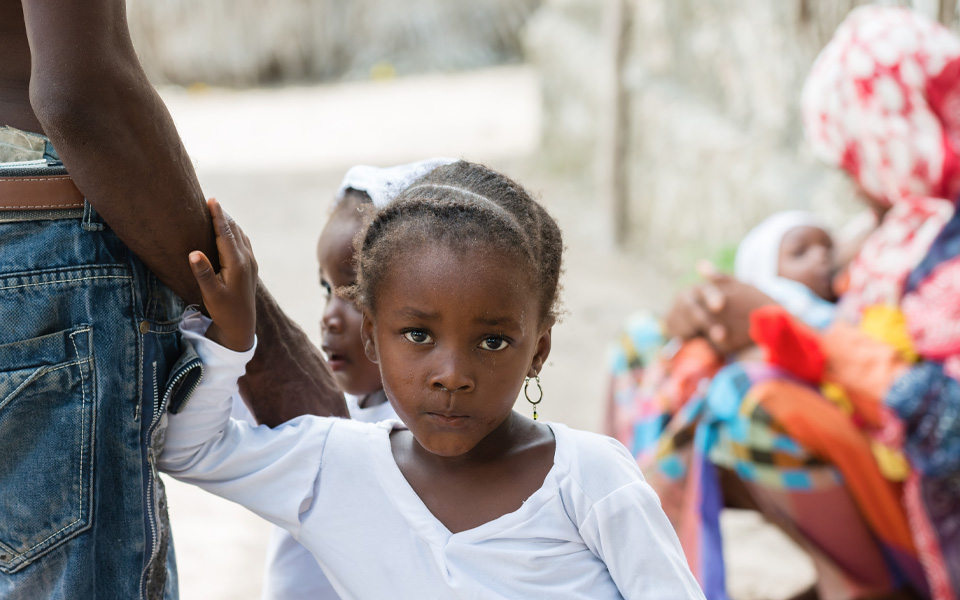 Image of a young girl in Sierra Leone holding her dads hand. 