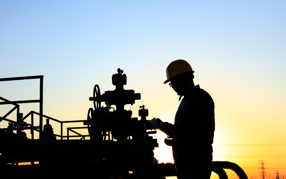 Photo of an energy sector worker in silhouette with a sunset behind him.