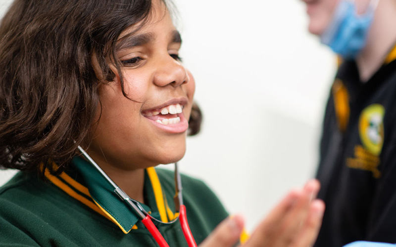 A close up image of a young Malpa participant speaking to the group in an animated way, wearing a green tshirt and a stethoscope.