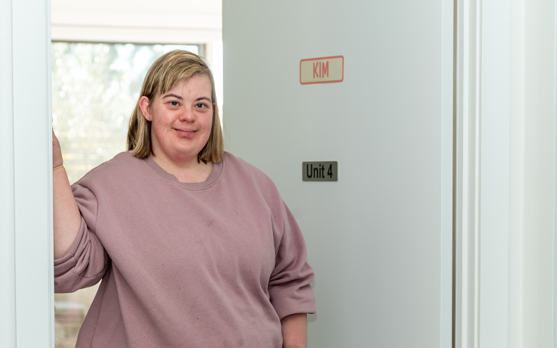 Photo of a Project Independence home owner standing in the doorway of her home, looking satisfied.