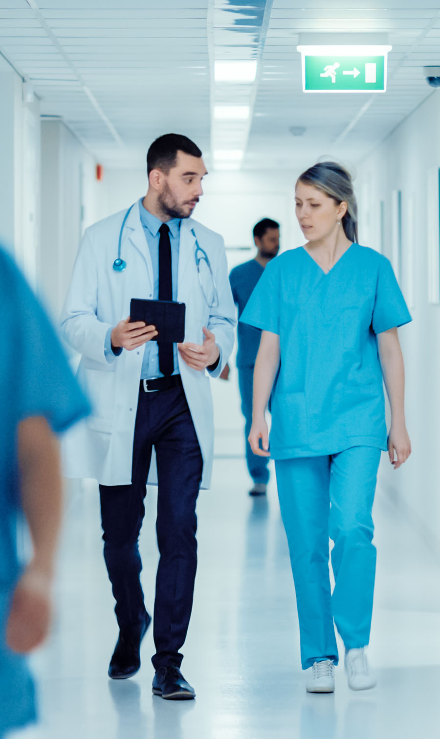 Image of a male and female clinician walking together down a hallway, talking.