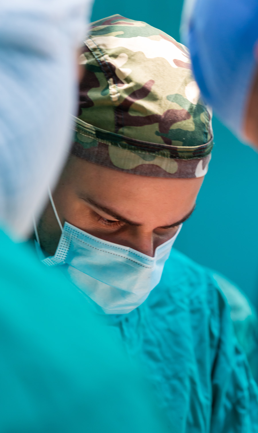 Photo displays a close up shot of a surgeon wearing a military cap.