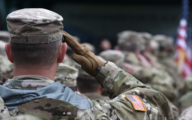 Photo shows the back of an American soldier, who is soluting.