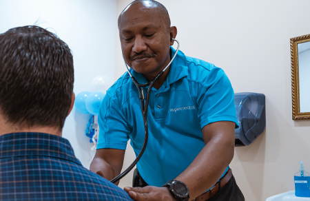 Photo shows an Aspen Medical clinician in PNG tending to a patient, wearing an AM aqua polo.