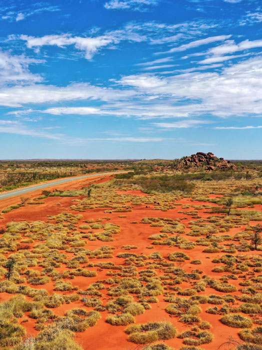 Photo shows a red earth landscape in Australia with a blue sky.