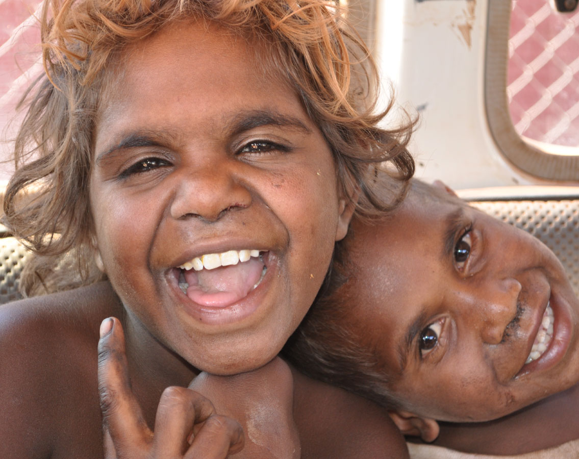 Photo shows two First Nations kids smiling and laughing in Northern Territory.
