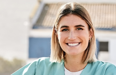 Photo shows a young Australian nurse outside, smiling.