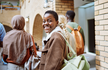 Photo shows a young African-looking woman walking with crowd but turning back to the camera.