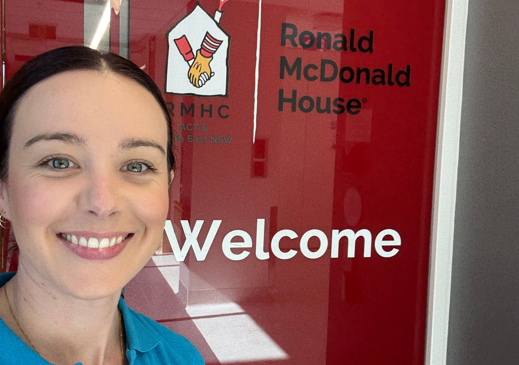 Female standing beside a welcome sign at Ronald McDonald House Charities 