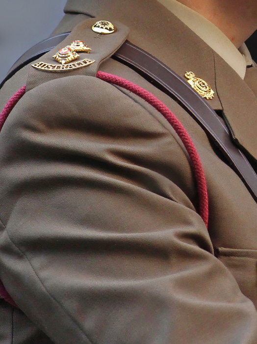 Photo is a close up of the shoulder of an Australian soldier marching.