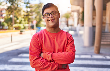 Photo shows a young man wearing a red jumper, with disability.