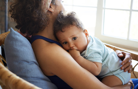 Photo shows a young boy slight on his mothers chest.