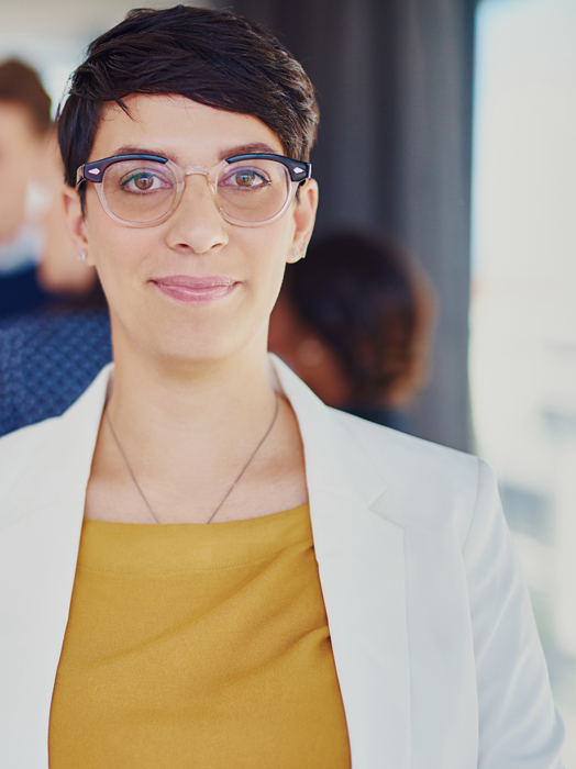 Image of a professional woman with short dark hair and glasses, looking confidently at the camera.