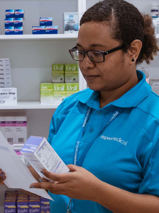 Photo shows an Aspen Medical clinician in Papua New Guinea looking through medicines in a storage room.