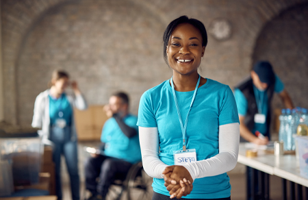 Photo shows a female aid worker wearing aqua and clasping her hands together.