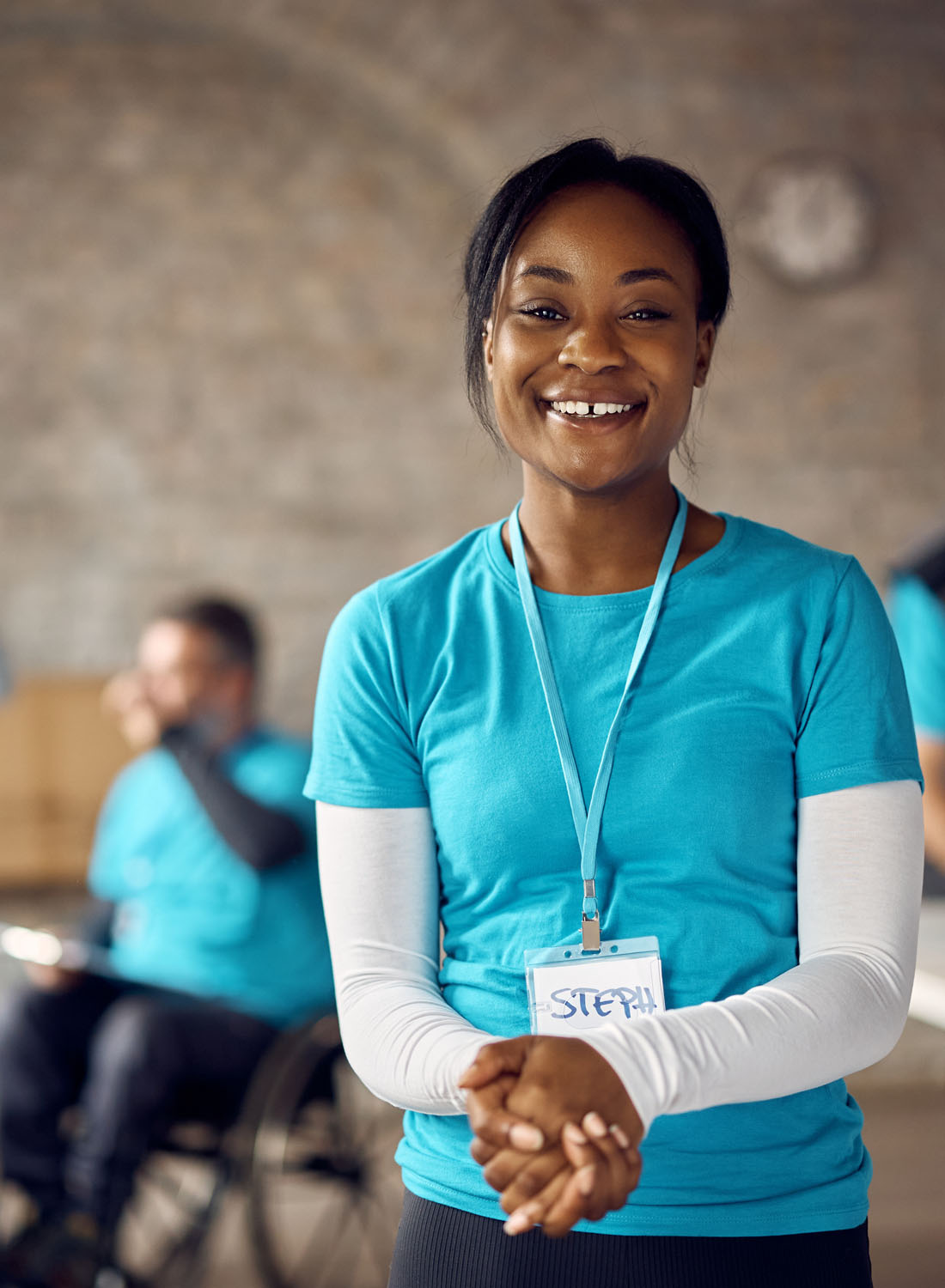 Photo shows a female aid worker wearing aqua and clasping her hands together.
