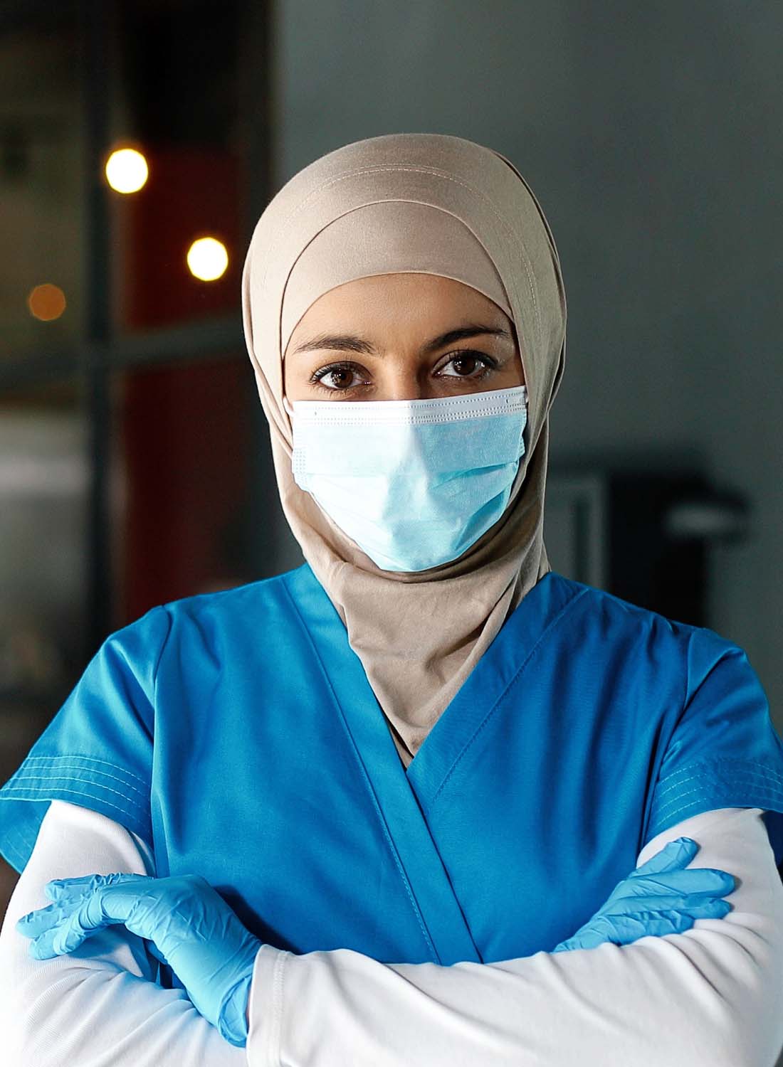 Photo shows a young Emirati clinician wearing a mask and head scarf.