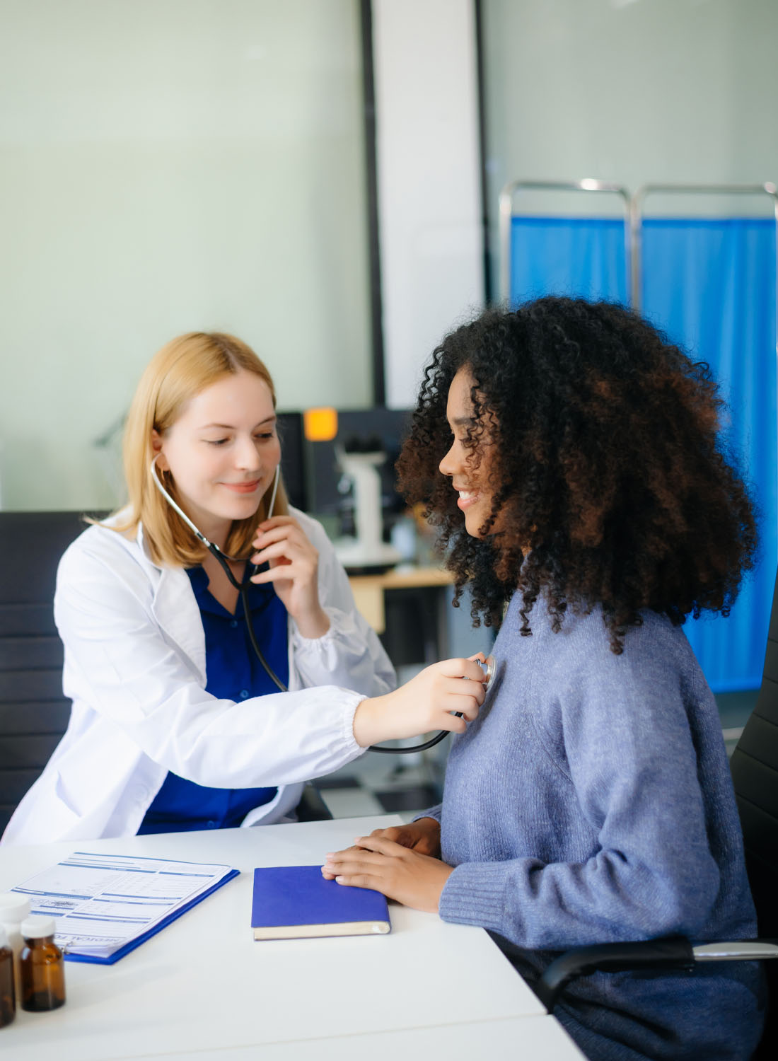 Image shows a young female clinician checking the heart rate of a patient.