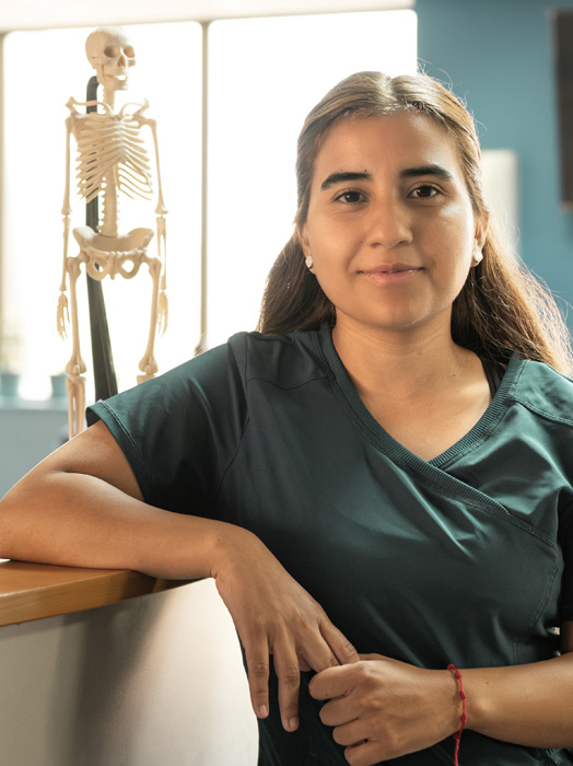 Photo shows a healthcare trainer with a skeleton hanging in the background.