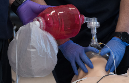 Photo shows someone being trained to use an air device on a dummy.