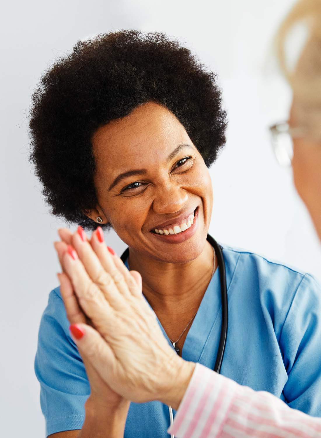 Photo shows a female clinician with dark hair holding the hand of an elderly patient.