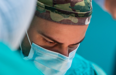 photo shows an army surgeon wearing full PPE and performing surgery.