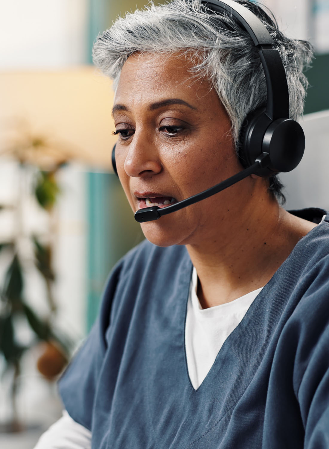 Image shows a female virtual care clinician taking a call on a headset.