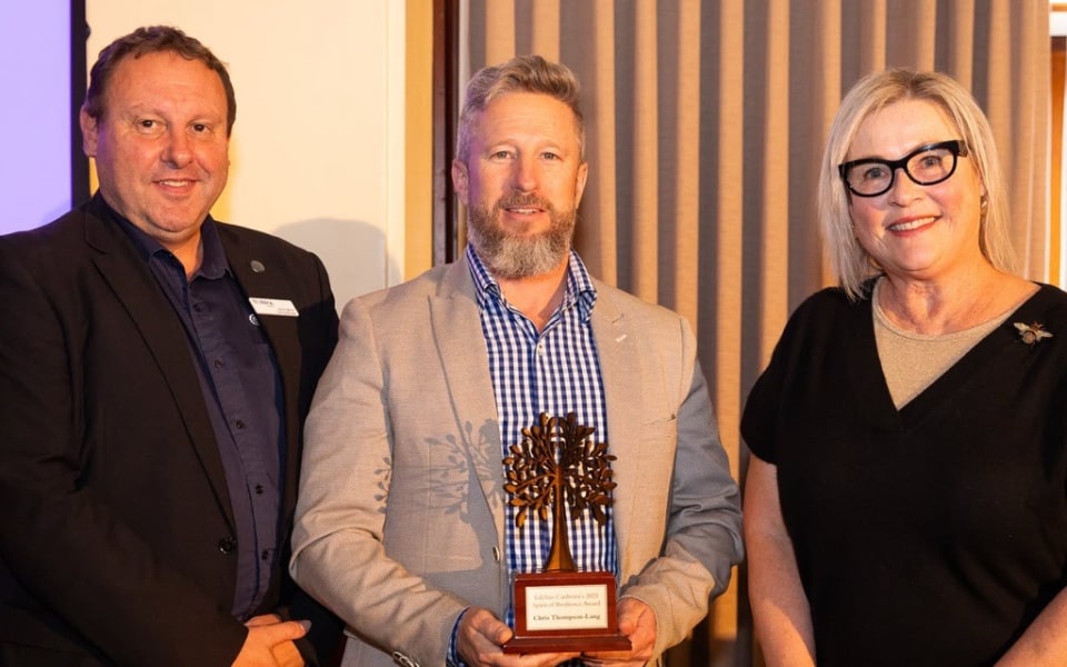 Man receiving trophy standing between two other people 