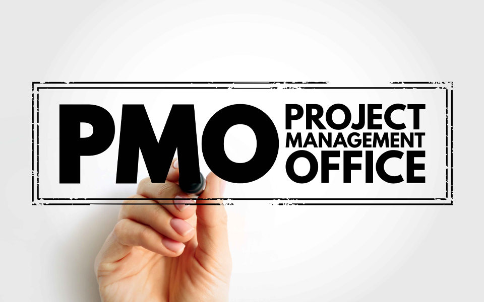 Image shows a hand stamping 'PMO: Project Management Office' on the screen.