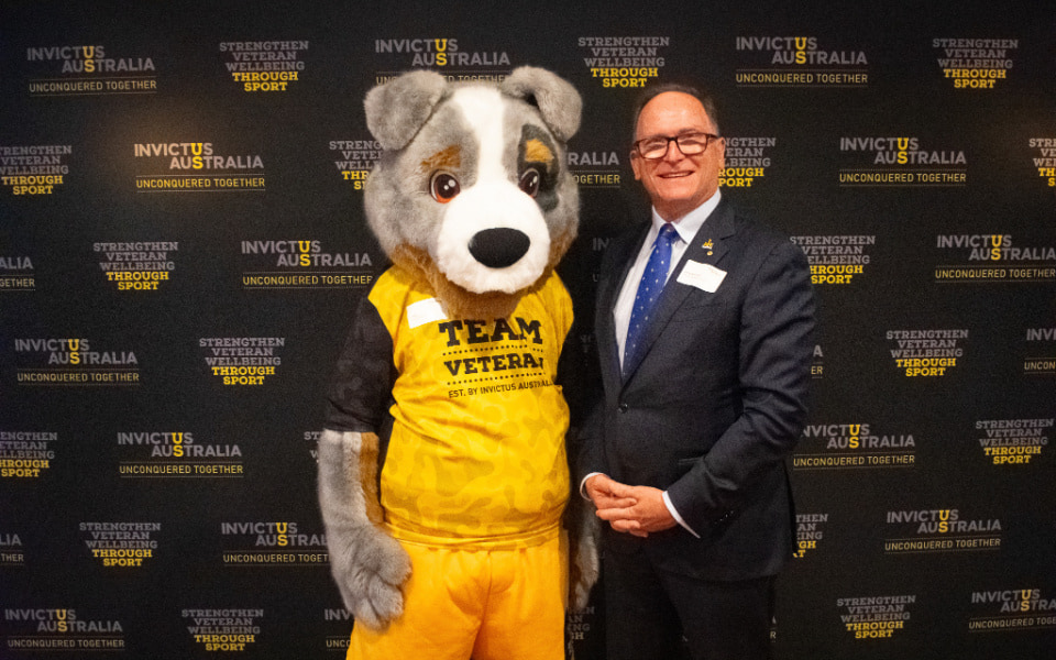 Glenn Keys with the Invictus mascot against a branded backdrop