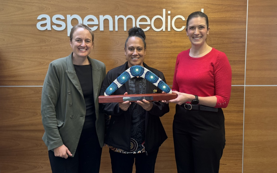 Three women standing against a branded corporate logo on a wall