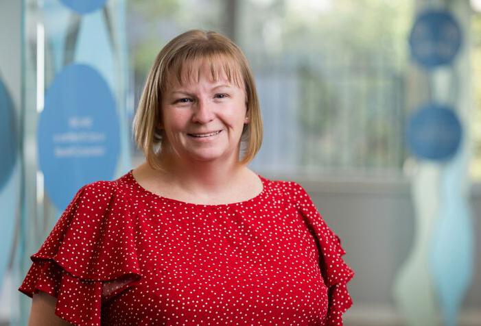 A professional portrait of Aspen Medical's Deployable Health Capability Lead, Kelly-Ann King, in a modern office setting.