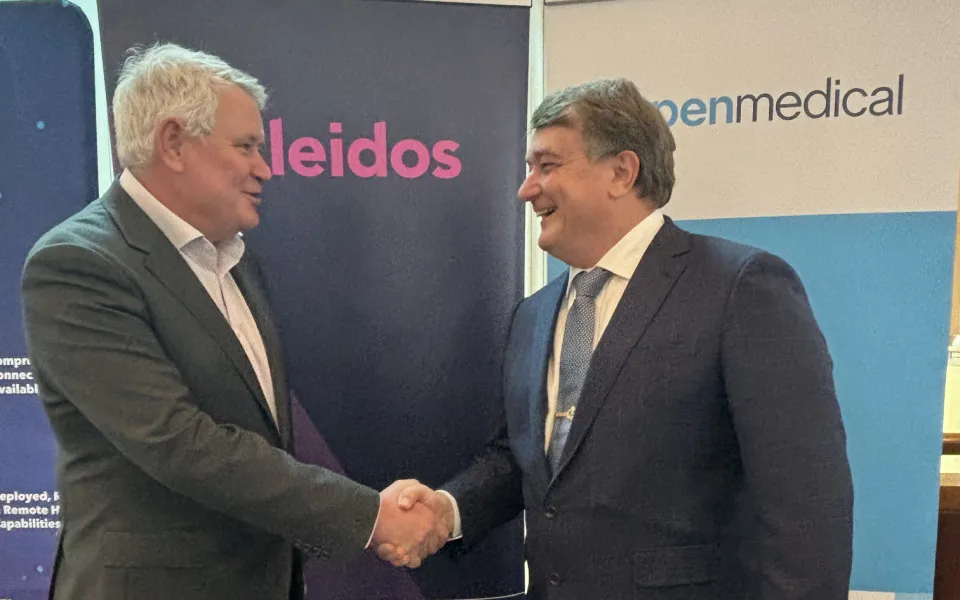 Two men shaking hands in front of branded banners