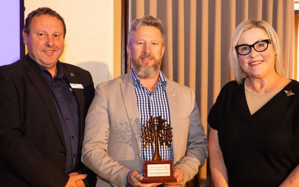 Man receiving trophy standing between two other people