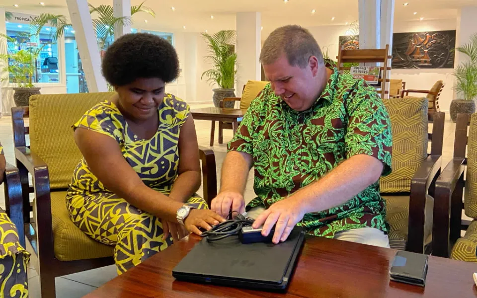 Two people sitting at a table with a laptop computer.