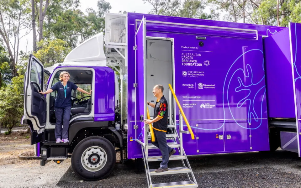 Two people with a large mobile clinic vehicle 